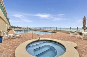 a swimming pool with a hot tub next to the ocean at Ponce Inlet Florida Breathtaking Oceanfront Penthouse Villa! in Ponce Inlet