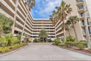 a large building with palm trees in front of it at Ponce Inlet Florida Breathtaking Oceanfront Penthouse Villa! in Ponce Inlet