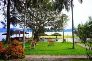 a playground with colorful swings in a park next to the water at Hotel Pandu Lakeside Tuktuk in Tuktuk Siadong