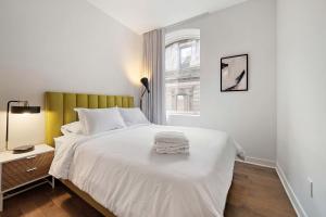 ein Schlafzimmer mit einem weißen Bett und einem Fenster in der Unterkunft The Nomad Saint Jacques in Montreal