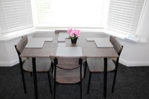 a wooden table with chairs and a vase of flowers at Awesome Coventry Home from Home for Business Contractors and Suitable for families with Free WI-FI Free Parking in Coventry