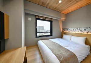 Un dormitorio con una cama grande y una ventana en HOTEL AMANEK Kamata-Eki Mae en Tokio