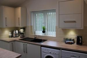 a kitchen with white cabinets and a sink and a window at Awesome Coventry Home from Home for Business Contractors and Suitable for families with Free WI-FI Free Parking in Coventry