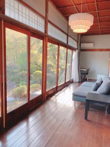 uma sala de estar com uma cama e janelas grandes em 温泉付きの一軒家を借りよう em Beppu