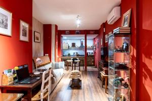 a living room with red walls and a desk with a laptop at Apartamento Mikaela Alcalá de Henares in Alcalá de Henares