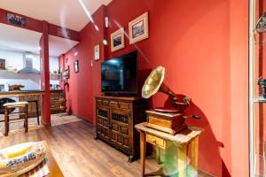 a living room with a red wall and a television at Apartamento Mikaela Alcalá de Henares in Alcalá de Henares