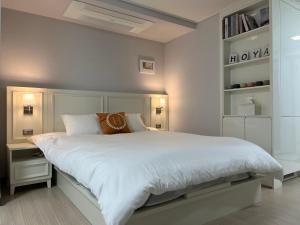 a white bedroom with a large bed with white sheets at Hoya stay in Yeosu