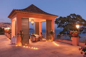 a gazebo with people sitting at tables on a patio at Reid's Palace, A Belmond Hotel, Madeira in Funchal