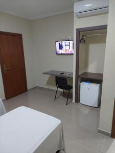 a room with a bed and a table and a desk at Apoema Hotel in Cuiabá