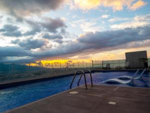 a swimming pool on top of a building with a sunset at iFreses, Lofts Full equipped whith Pool, air-conditioning, spectacular view of the city in Curridabat