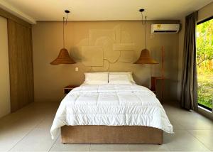 - une chambre avec un lit blanc et deux lampes suspendues dans l'établissement Casa Toronja, à Montenegro