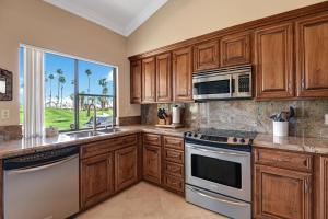 a kitchen with wooden cabinets and stainless steel appliances at VB944 - Triple Fairway View - Palm Valley CC in Palm Desert