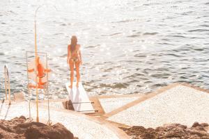 a woman in a bikini standing on a surfboard in the water at Reid's Palace, A Belmond Hotel, Madeira in Funchal