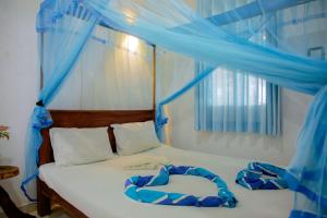 a bedroom with a bed with blue drapes at New Cormorant Lake Resort & Yala Safari Place in Tissamaharama