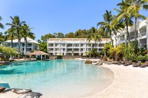 a swimming pool in front of a resort at In the Tropics Balcony Oasis at The Beach Club in Palm Cove