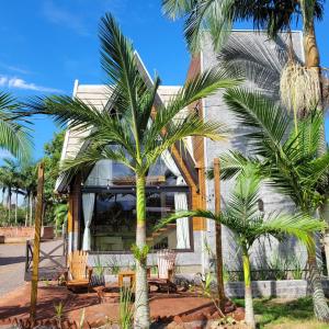 uma casa com palmeiras em frente em AriMara Chalés & Ecoturismo em Praia Grande