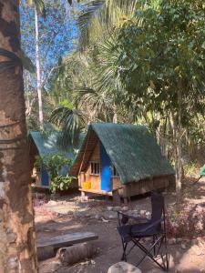 een klein huis met een groen dak en een stoel bij MoRue's Den in Mabini