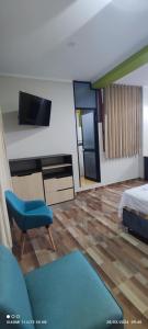 1 dormitorio con 1 cama, TV y silla en casa sol residencial, en Tarapoto