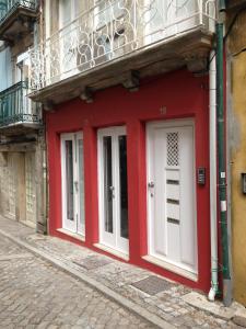 a red building with a white door on a street at APOSENTUS - St Francisco Apartment in Porto
