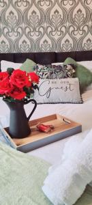 a tray with a vase with roses on a bed at The Upside down House near Coop Live Arena , Etihad and Mcr City Centre in Manchester