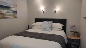 um quarto com uma cama com lençóis brancos e almofadas em Coastal Condo em Waitarere