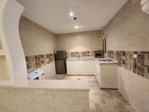 a kitchen with white cabinets and a black refrigerator at فندق كنف - kanaf hotel in Ash Sharāʼi‘