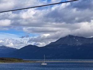 a boat in the water with mountains in the background at Casa, central a orilla de playa in Puerto Williams
