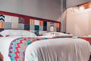 ギリ・アイルにあるCindra 1 BR Deluxe Room Gili Air NE59のベッドルーム(白いベッド、カラフルなヘッドボード付)