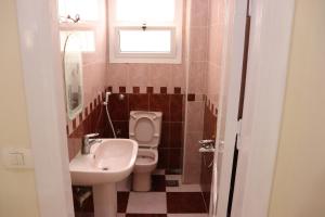 ein Bad mit einem Waschbecken, einem WC und einem Fenster in der Unterkunft Sandy House in Madinat as-Sadis min Uktubar