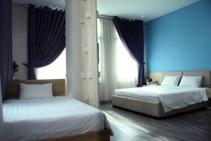 two beds in a bedroom with blue walls and windows at Khách sạn Phước Lộc Thọ 2 - 福禄寿 in Ho Chi Minh City
