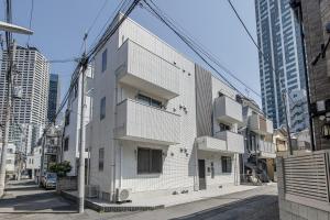 a white building on a city street with tall buildings at Felice Nishi-Shinjuku in Tokyo