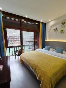 a bedroom with a large bed and a balcony at Fenghuang Ancient Town Lazy Cat Riverside Inn in Fenghuang