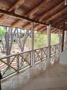 uma varanda com um telhado de madeira com árvores ao fundo em Mkuu House em Melinde
