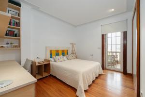 Un dormitorio blanco con una cama y un escritorio. en La Casa De Rita, en Baiona