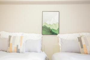 two beds with white sheets and a picture on the wall at Walk to Ikebukuro Station. SYo in Tokyo