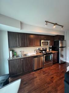 a kitchen with wooden cabinets and stainless steel appliances at Downtown Toronto Cozy Suite in Toronto