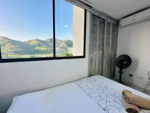 a bedroom with a bed and a window with mountains at Acogedor apartamento Rodadero Santa Marta con vista al Lago in Santa Marta +31 photos