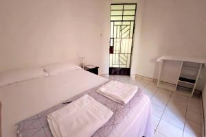 a bedroom with a white bed with two towels on it at CENTRICO, COMODO Y CON ACCESO A PARADEROS in Chiclayo
