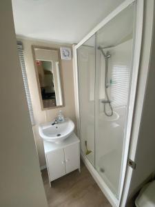 a white bathroom with a shower and a sink at Cosy caravans 10 berth caravan on Butlins Skegness in Skegness