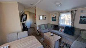 een woonkamer met een bank en een tafel bij Cosy caravans 10 berth caravan on Butlins Skegness in Skegness