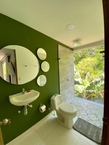 baño verde con aseo y lavamanos en ORIGEN FINCA HOTEL, en Quimbaya