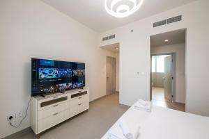 a white bedroom with a large flat screen tv at 3 Bedrooms Forte tower 1- Downtown Skylight in Dubai