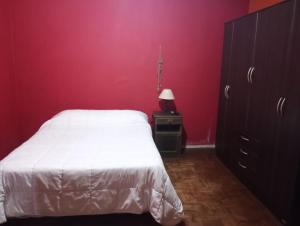 a bedroom with a white bed and a red wall at Hermosa casa para vacaciones in Guaymallen