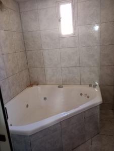 a white bath tub in a bathroom with a window at Hermosa casa para vacaciones in Guaymallen