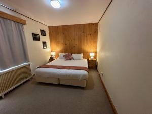 een slaapkamer met een bed, 2 lampen en een raam bij Peer Gynt Ski Lodge in Perisher Valley