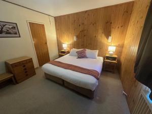 a bedroom with a large bed with two lamps on two tables at Peer Gynt Ski Lodge in Perisher Valley