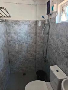 a bathroom with a white toilet and a shower at Arzel's Tiny House in Mangatarem