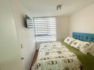 1 dormitorio con 1 cama con cabecero azul y ventana en Casa de Moneda Downtown en Santiago