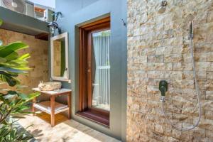 a bathroom with a shower with a stone wall at Ammora 1 BR Deluxe Suite NE60 in Gili Air