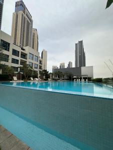 a large swimming pool in a city with tall buildings at Burj Khalifa View & Creek lagoon in Dubai